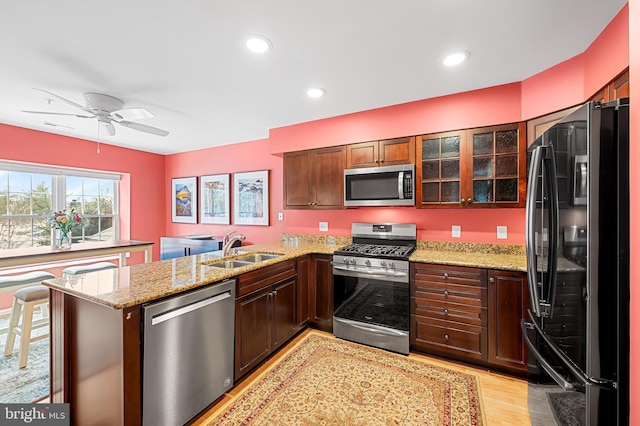 kitchen featuring sink, kitchen peninsula, stainless steel appliances, and light wood-type flooring