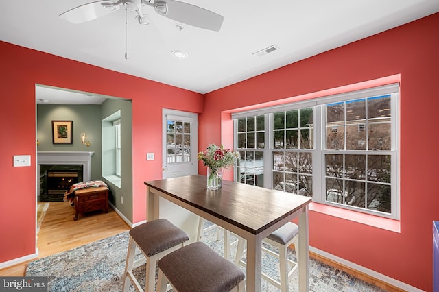 dining area with ceiling fan, wood-type flooring, and a high end fireplace