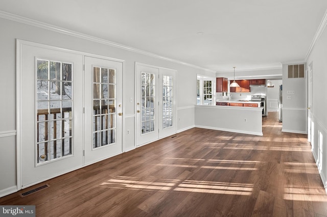 unfurnished living room featuring a healthy amount of sunlight, crown molding, and dark wood-type flooring