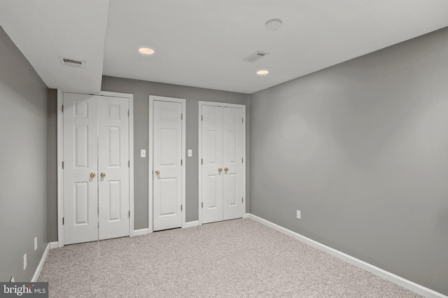 unfurnished bedroom with two closets and carpet flooring