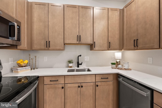 kitchen featuring stainless steel appliances, light stone countertops, sink, and backsplash