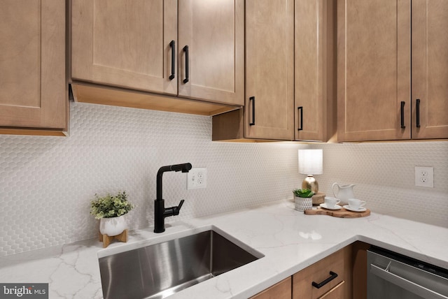 kitchen with light stone counters, sink, backsplash, and stainless steel dishwasher