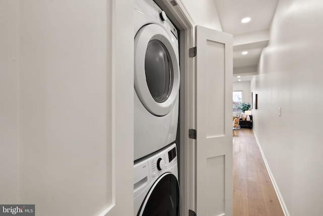 washroom featuring stacked washer / drying machine and light hardwood / wood-style flooring