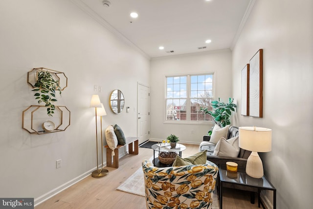 sitting room with ornamental molding and light hardwood / wood-style flooring