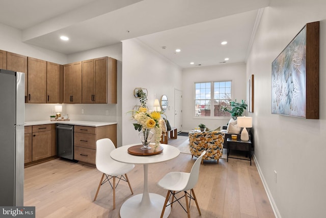 kitchen with stainless steel appliances, crown molding, and light hardwood / wood-style floors