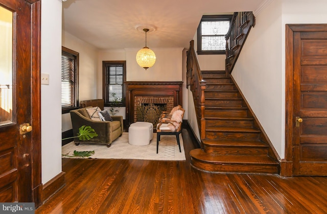 entrance foyer featuring plenty of natural light, dark wood-type flooring, a notable chandelier, and a brick fireplace