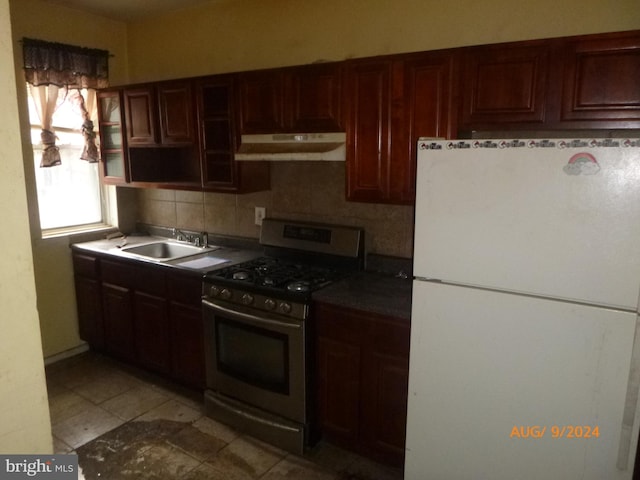 kitchen featuring backsplash, white fridge, sink, and gas stove