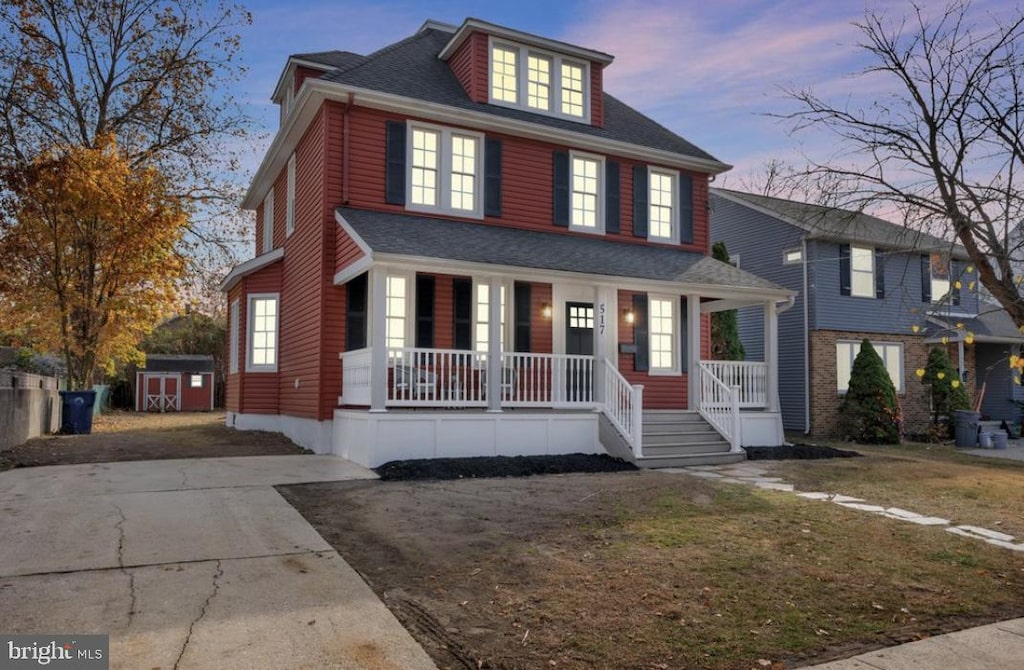 view of front of home featuring a yard, covered porch, and a storage unit