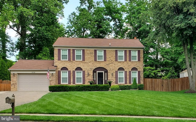 colonial-style house featuring a garage and a front lawn