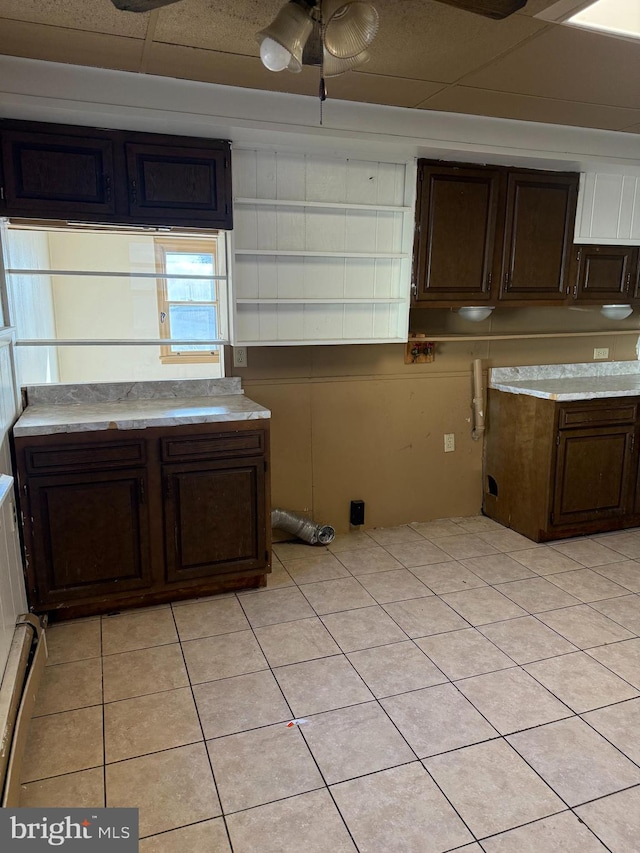 kitchen featuring dark brown cabinetry, ceiling fan, and light tile patterned floors