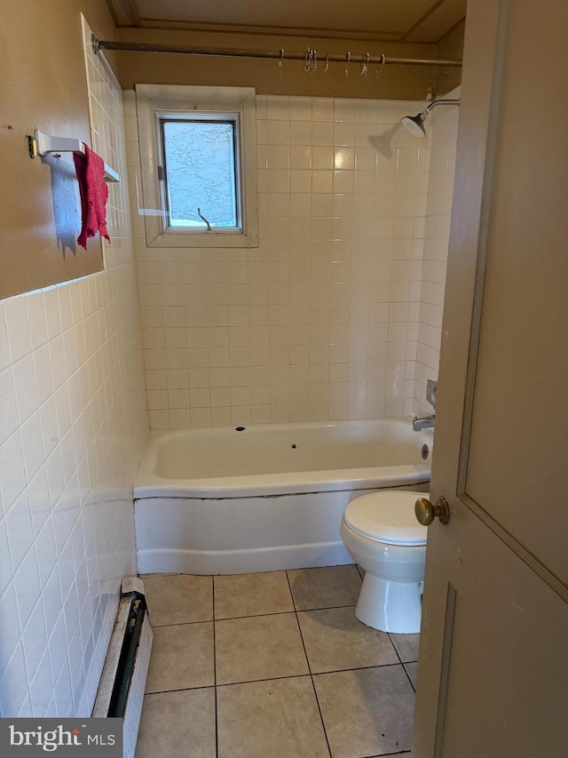 bathroom featuring baseboard heating, tile patterned floors, toilet, tile walls, and tiled shower / bath