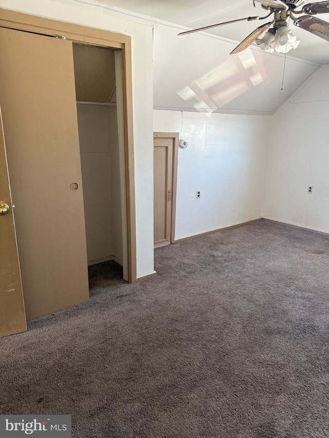 unfurnished bedroom with ceiling fan, vaulted ceiling, and dark colored carpet