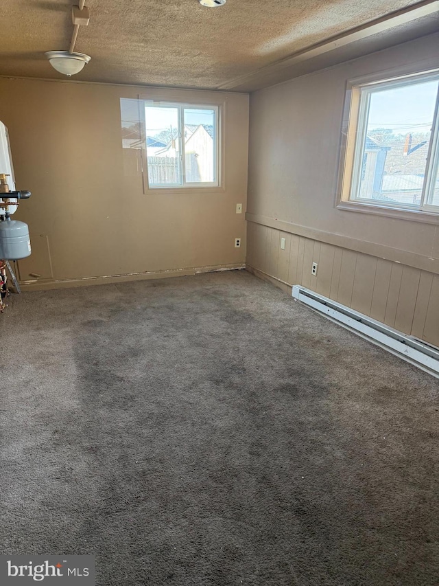 carpeted spare room with a baseboard radiator and a textured ceiling