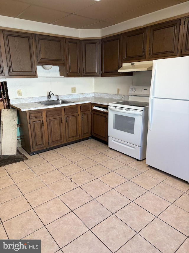 kitchen featuring dark brown cabinets, sink, light tile patterned floors, and white appliances