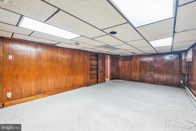 basement with carpet flooring, wood walls, and a drop ceiling