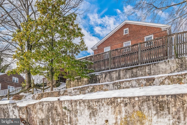 snow covered back of property with a balcony