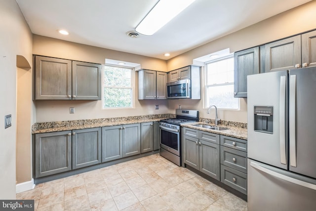 kitchen featuring sink, light stone counters, and appliances with stainless steel finishes