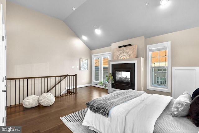 bedroom with a multi sided fireplace, multiple windows, vaulted ceiling, and dark wood-type flooring