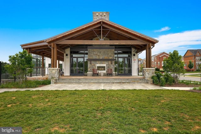 back of house featuring french doors, a lawn, and a stone fireplace