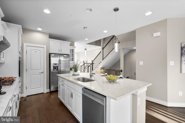 kitchen with decorative light fixtures, stainless steel appliances, a kitchen island with sink, and sink