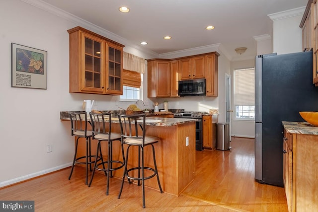 kitchen featuring crown molding, light wood-type flooring, kitchen peninsula, and stainless steel appliances