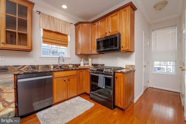 kitchen featuring ornamental molding, sink, appliances with stainless steel finishes, and dark stone counters