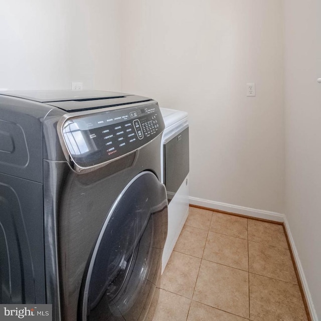 laundry area featuring light tile patterned floors and washing machine and clothes dryer