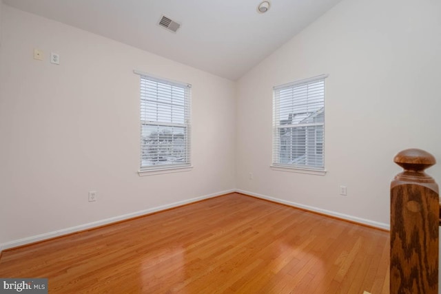 spare room with vaulted ceiling, light hardwood / wood-style flooring, and plenty of natural light