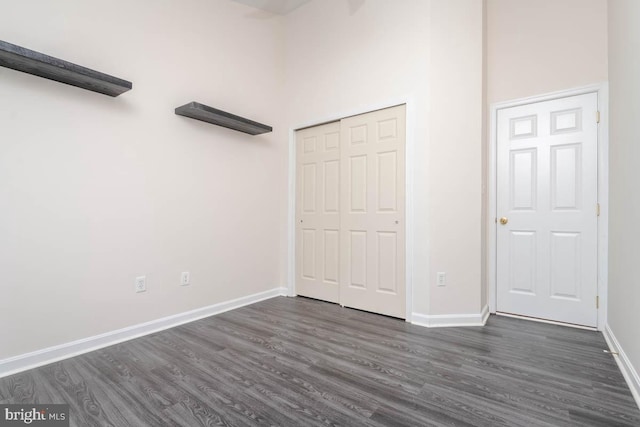 unfurnished bedroom featuring dark hardwood / wood-style flooring and a towering ceiling