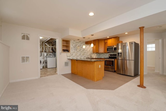 kitchen featuring hanging light fixtures, kitchen peninsula, light carpet, washer and clothes dryer, and appliances with stainless steel finishes