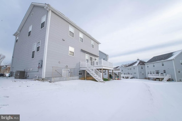 snow covered property with a deck and central AC