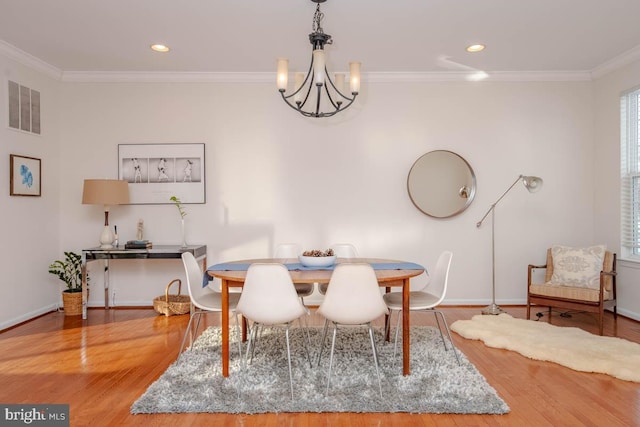 dining area with a chandelier, hardwood / wood-style flooring, and ornamental molding