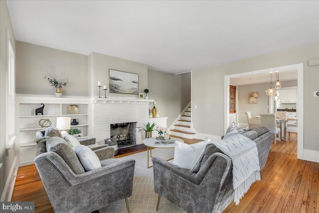 living room with a brick fireplace and hardwood / wood-style floors