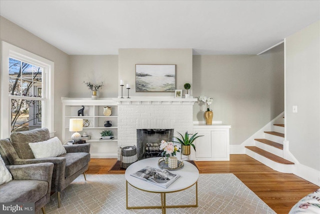 living room with wood-type flooring and a brick fireplace