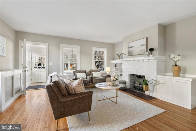 living room with light hardwood / wood-style flooring and a brick fireplace