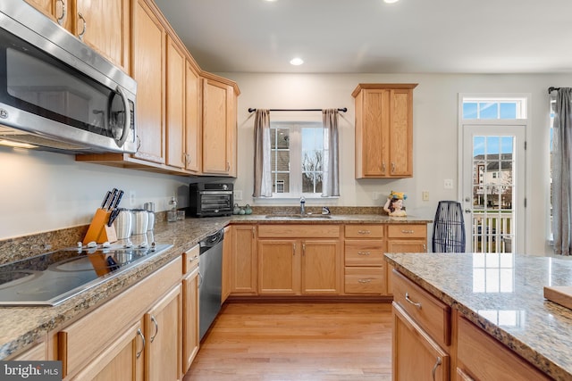 kitchen featuring appliances with stainless steel finishes, light stone counters, sink, light brown cabinets, and light hardwood / wood-style flooring