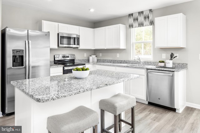 kitchen with a center island, stainless steel appliances, white cabinetry, and sink