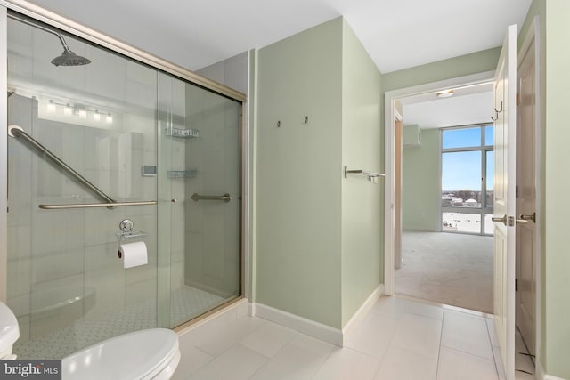 bathroom with tile patterned floors, toilet, a shower with door, and expansive windows