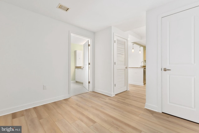 unfurnished bedroom with ensuite bath and light hardwood / wood-style flooring