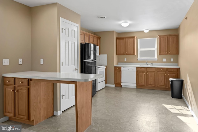 kitchen featuring black refrigerator, stove, a kitchen breakfast bar, sink, and dishwasher