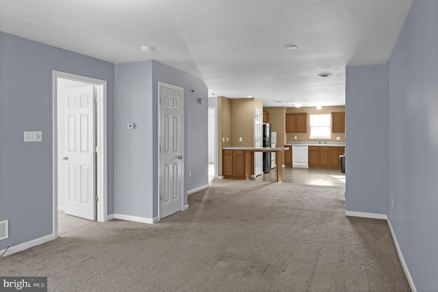 unfurnished living room with light colored carpet and sink