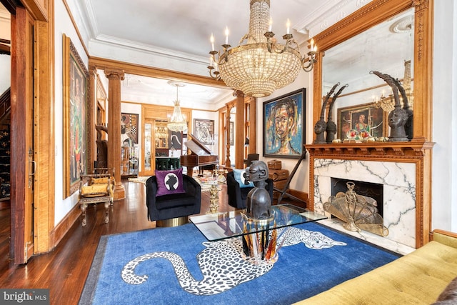 living room featuring dark wood-type flooring, a notable chandelier, a fireplace, ornamental molding, and ornate columns