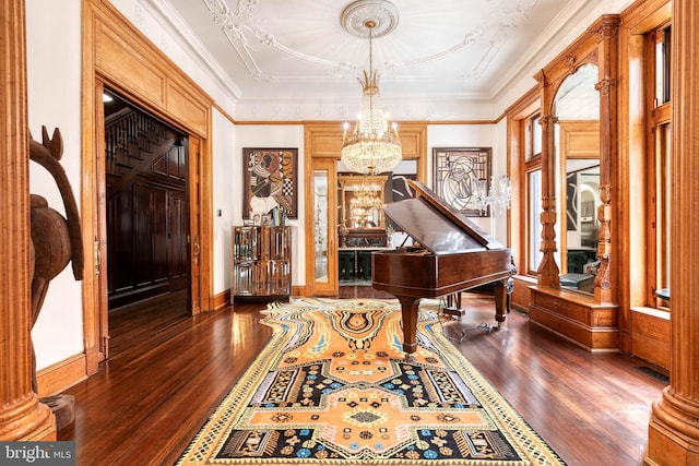 miscellaneous room featuring crown molding, dark wood-type flooring, decorative columns, and a chandelier