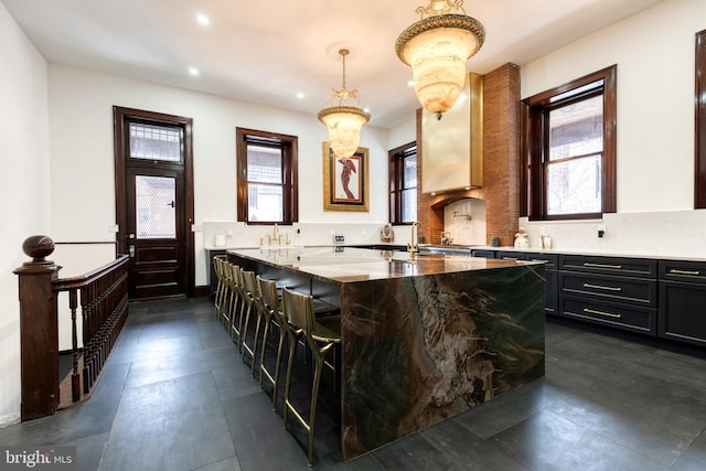 kitchen with tasteful backsplash, light stone counters, a center island, a kitchen breakfast bar, and pendant lighting