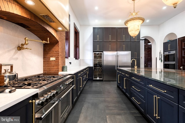 kitchen with high end appliances, tasteful backsplash, decorative light fixtures, beverage cooler, and dark stone counters