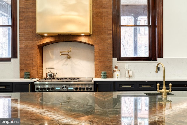 kitchen with stainless steel gas cooktop, brick wall, sink, and a wealth of natural light