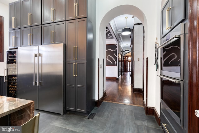 kitchen with gray cabinets, appliances with stainless steel finishes, wine cooler, light stone counters, and crown molding