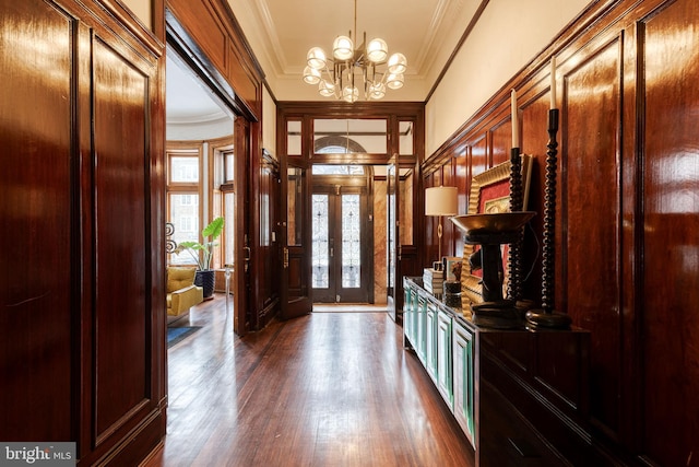 foyer entrance with french doors, dark hardwood / wood-style flooring, a chandelier, and crown molding