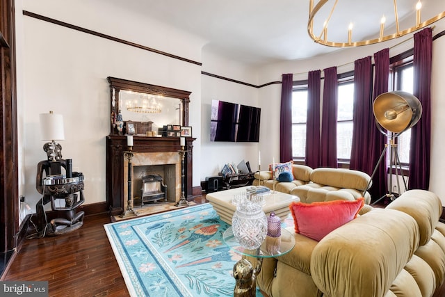 living room featuring plenty of natural light, dark hardwood / wood-style floors, an inviting chandelier, and a high end fireplace