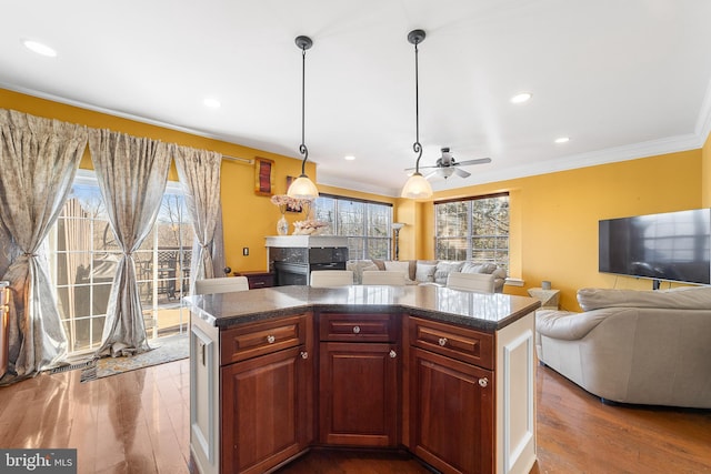 kitchen featuring hanging light fixtures, wood-type flooring, a kitchen island, and ceiling fan